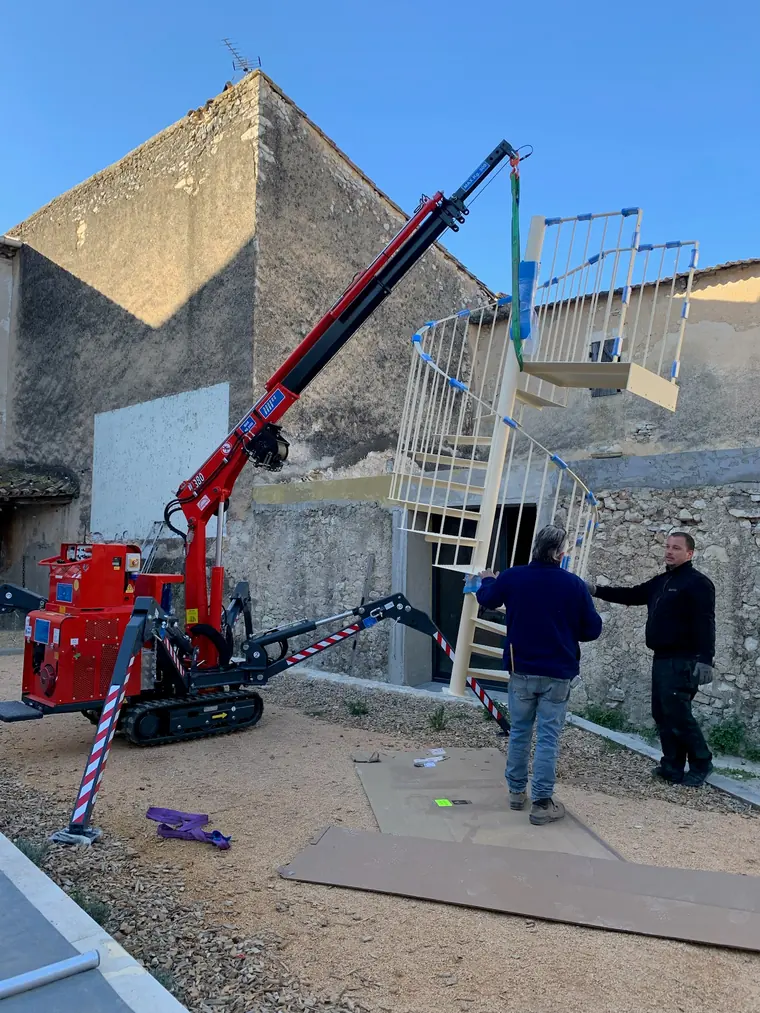 Mini-grue araignée dans une cour de village en pierre