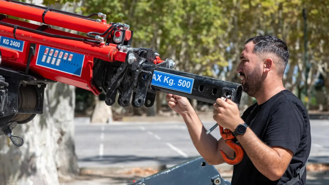 Mains de l'opérateur sur la tête de flèche de la mini-grue, plaque indiquant la charge maximale de 500 kg