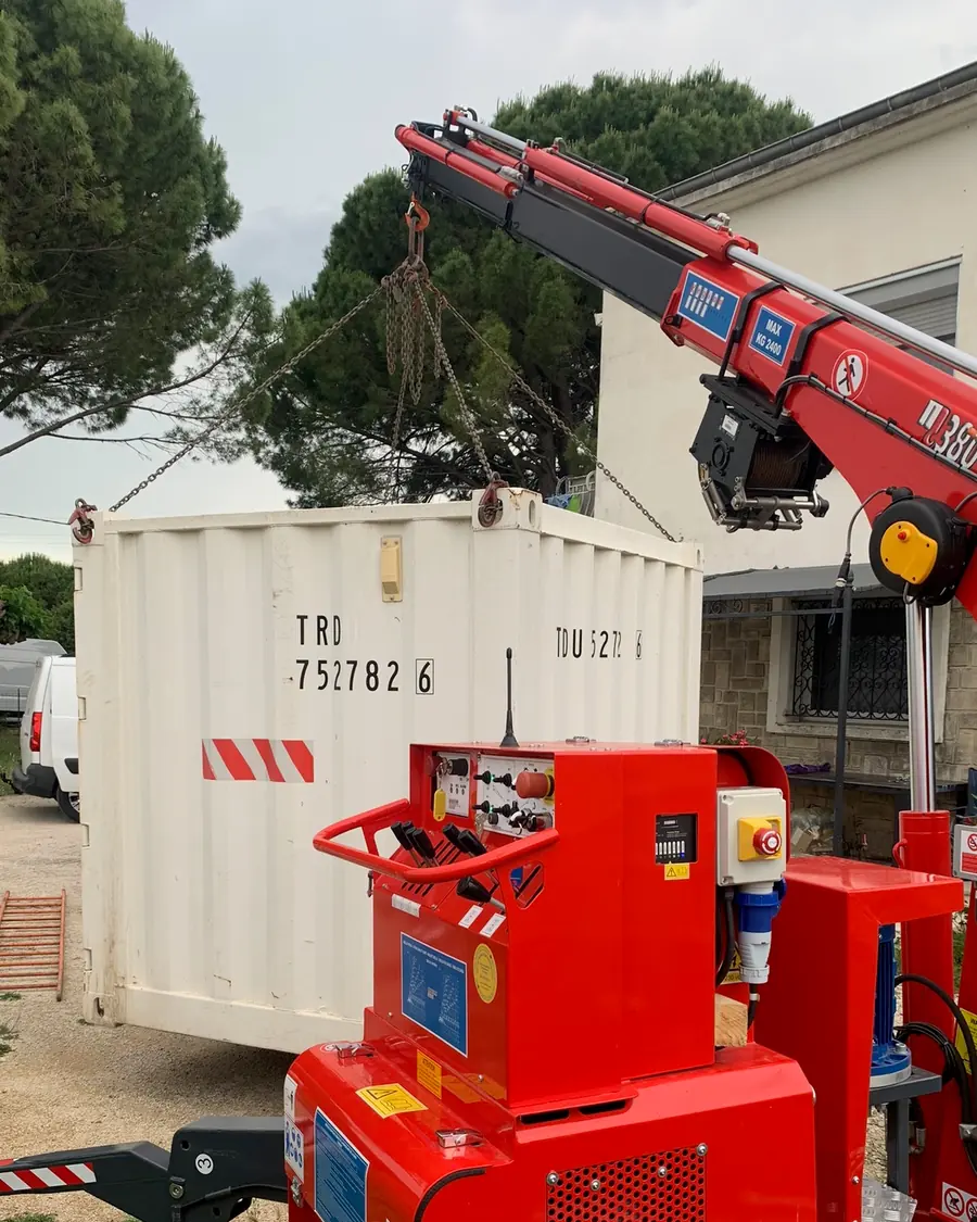 Mini-grue araignée levant un conteneur maritime élingué par des chaînes
