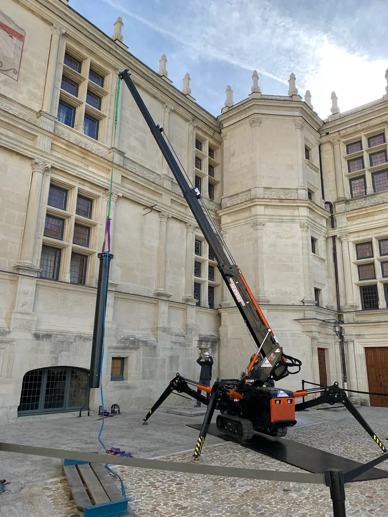 Mini-grue araignée devant une façade en pierre de taille