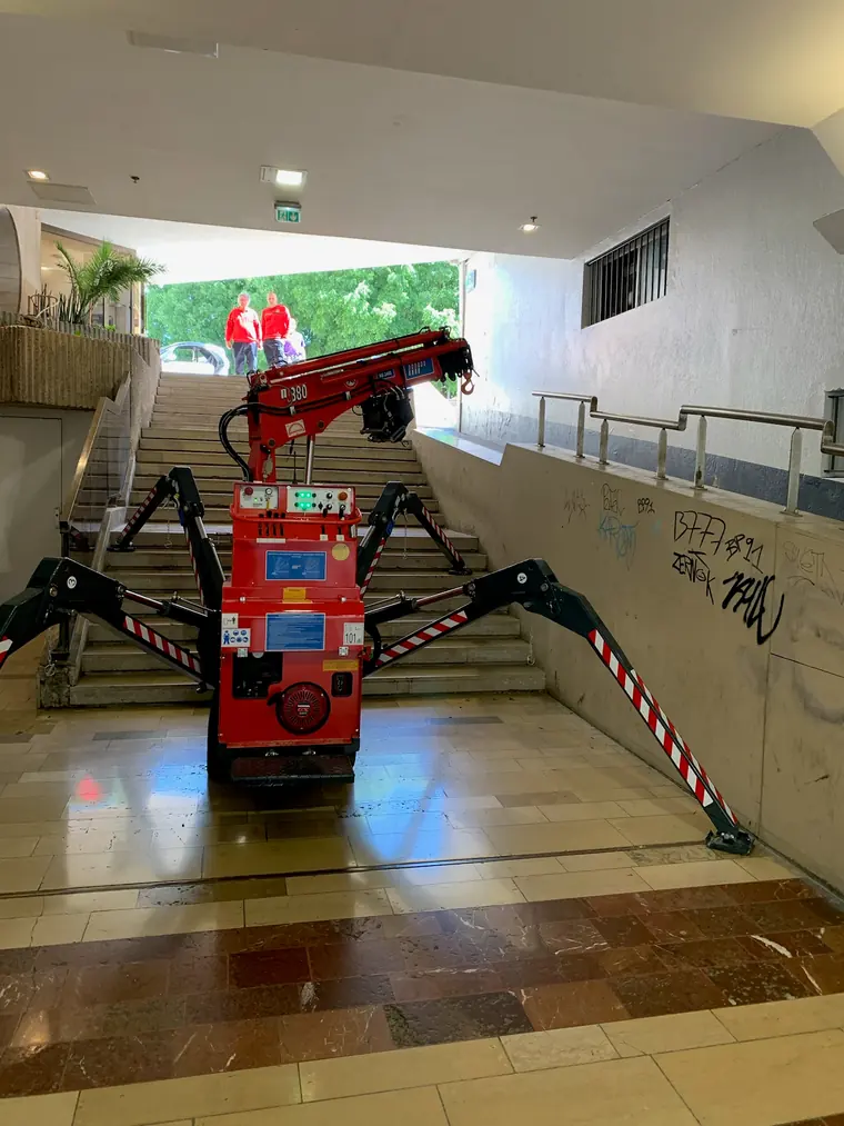 Mini-grue araignée engagée dans une rampe de parking souterrain